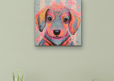 Farbstarkes Pop-Art-Gemälde eines flauschigen Welpen an einer graugrünen Wand über einem eleganten, hellen Konsolentisch.