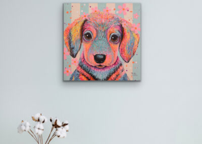 Quadratisches Kunstwerk des farbenfrohen Dackels „Otto: Personality“ an einer hellgrauen Wand über einer Bodenvase mit Baumwollzweigen.