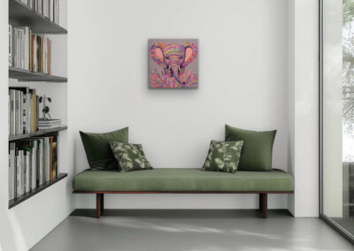 Farbenfrohes Elefanten-Portrait im Pop-Art-Stil als Wandbild über einer grünen Sitzbank mit Kissen in einer hellen Raumecke.