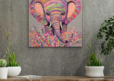 Farbstarkes Elefanten-Gemälde im Pop-Art-Stil an einer strukturierten grauen Wand in Sichtbeton-Optik über einem Holz-Sideboard mit zwei grünen Pflanzen.