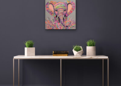 Quadratisches, buntes Neo-Pop-Art Gemälde eines Elefanten an einer dunkelgrauen Wand über einem minimalistischen Konsolentisch mit zwei kleinen Zimmerpflanzen.
