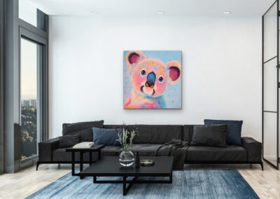 Modernes Pop-Art Koala-Gemälde als stilvolle Wanddekoration über einer großen, schwarzen Couch in einem hellen Wohnzimmer mit blauem Teppich.