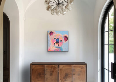 Farbenfrohes Koala-Portrait im Neo-Pop-Art-Stil platziert unter einem eleganten Rundbogen in einem hellen Eingangsbereich über einer Holzkommode.
