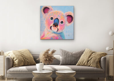 Farbenfrohes Koala-Wandbild im Pop-Art-Stil über einem gemütlichen grauen Sofa mit dekorativen Kissen und zwei runden, goldenen Couchtischen.