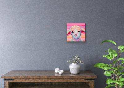 Farbenfrohes Pop-Art-Lamm-Portrait an einer strukturierten grauen Wand über einem dunklen Holztisch mit kleinen weißen Schalen und einer Vase.