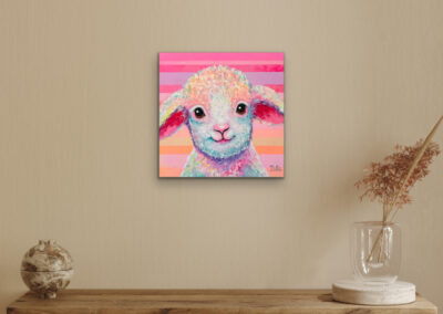 Buntes Pop-Art-Gemälde eines Schafes an einer beigefarbenen Wand über einem hölzernen Wandregal mit Trockenblumen in einer Glasvase.