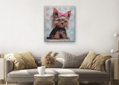 Modernes Neo-Pop-Art Gemälde eines Yorkshire Terriers mit rosa Schleife, präsentiert als farbenfrohes Wandbild über einer grauen Couch im Wohnzimmer.