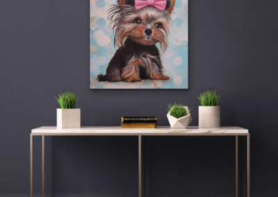 Modernes Neo-Pop-Art Gemälde eines Yorkshire Terriers mit rosa Schleife an einer dunkelgrauen Wand über einem minimalistischen Konsolentisch mit drei kleinen Zimmerpflanzen.