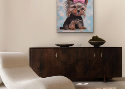 Buntes Hunde-Gemälde eines Yorkshire Terriers über einem dunklen Holz-Sideboard neben einem modernen, weißen Loungesessel.