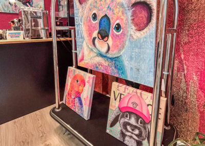 Einzigartige Kunst für Geschäftsräume: Großes, buntes Koala-Gemälde im modernen Neo-Pop-Art-Stil von Silke Timpe, präsentiert auf einem silbernen Hotelgepäckwagen als Inspiration für moderne Büros.