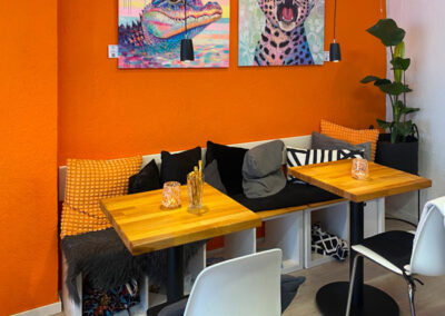 Wandgestaltung für ein Café oder Restaurant: Ein farbgewaltiges Krokodil- und ein Leopardengemälde im Neo-Pop-Art-Stil von Silke Timpe sorgen für ein inspirierendes Ambiente über den Tischen.