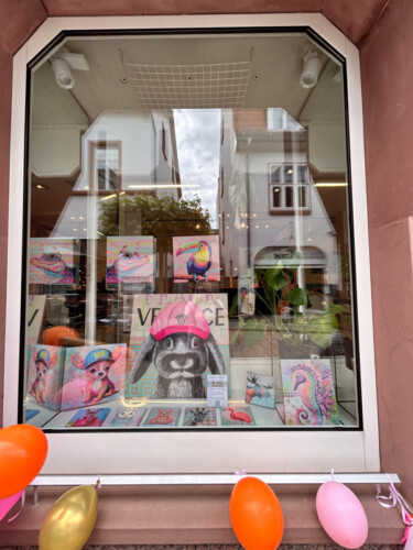 Schaufenstergestaltung mit moderner Kunst: Farbenfrohe Tierporträts von Silke Timpe im Neo-Pop-Art-Stil mit urbanen Einflüssen ziehen die Blicke im Außenbereich auf sich.