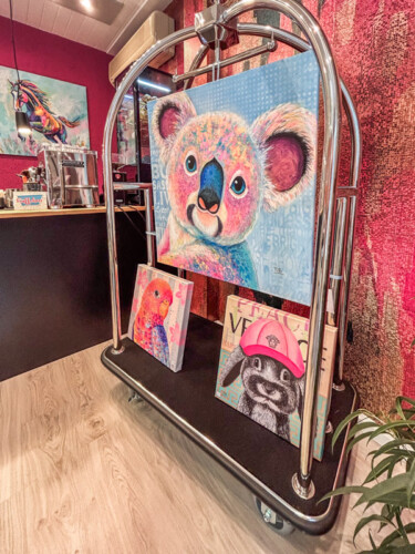 Einzigartige Kunst für Geschäftsräume: Großes, buntes Koala-Gemälde im modernen Neo-Pop-Art-Stil von Silke Timpe, präsentiert auf einem silbernen Hotelgepäckwagen als Inspiration für moderne Büros.